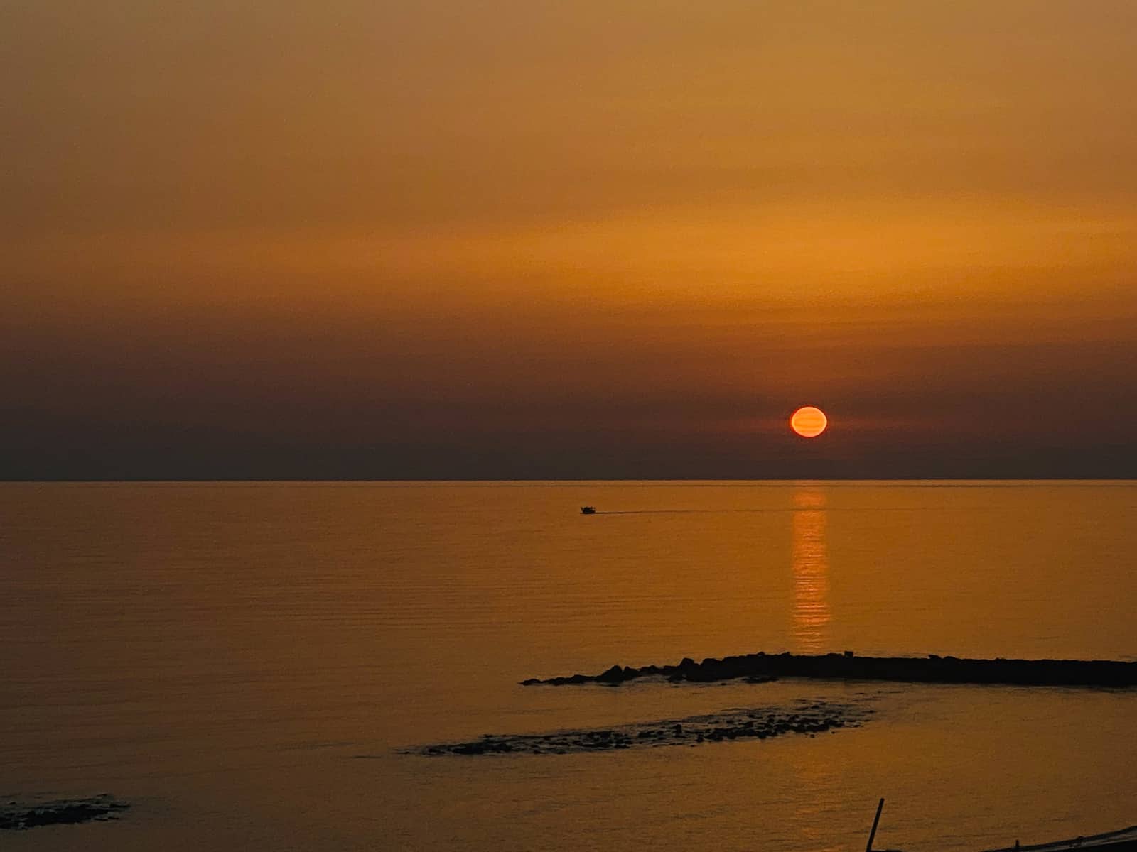 Orange sunset over the sea in Ostia with swallows and the harbour lights