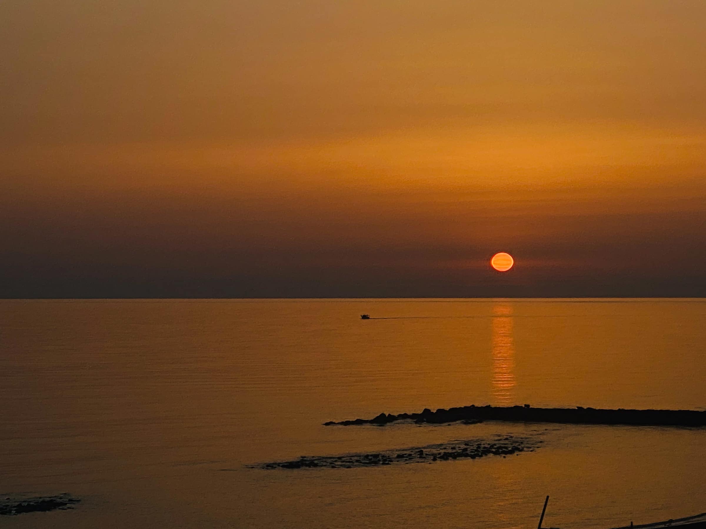 Orange sunset over the sea in Ostia with swallows and the harbour lights